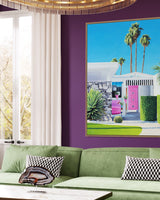 A beautiful piece of artwork brightens up a stylish living room with midcentury architecture and a vibrant pink front door, set against the stunning Palm Springs landscape