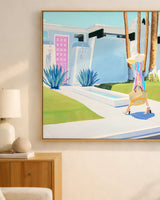 Framed artwork of a woman walking with a bag in a modern outdoor setting, hanging on a wall.